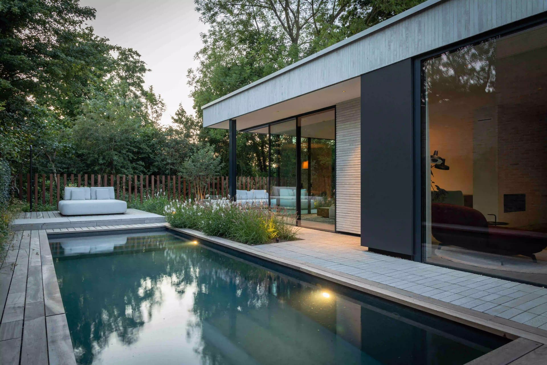 Evening view of illuminated modern garden with pool and contemporary architecture