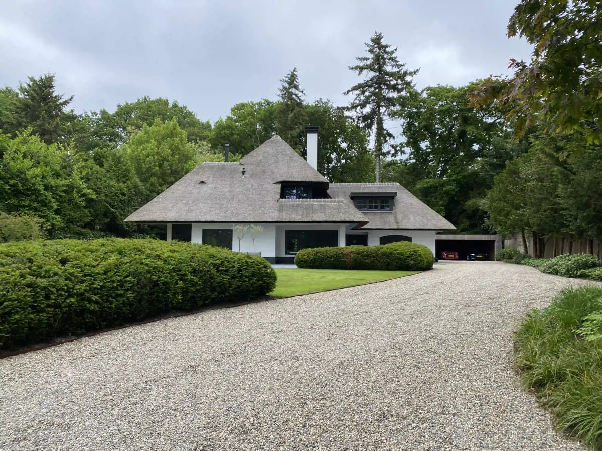 Traditionele boerderij met rieten dak en grindoprit