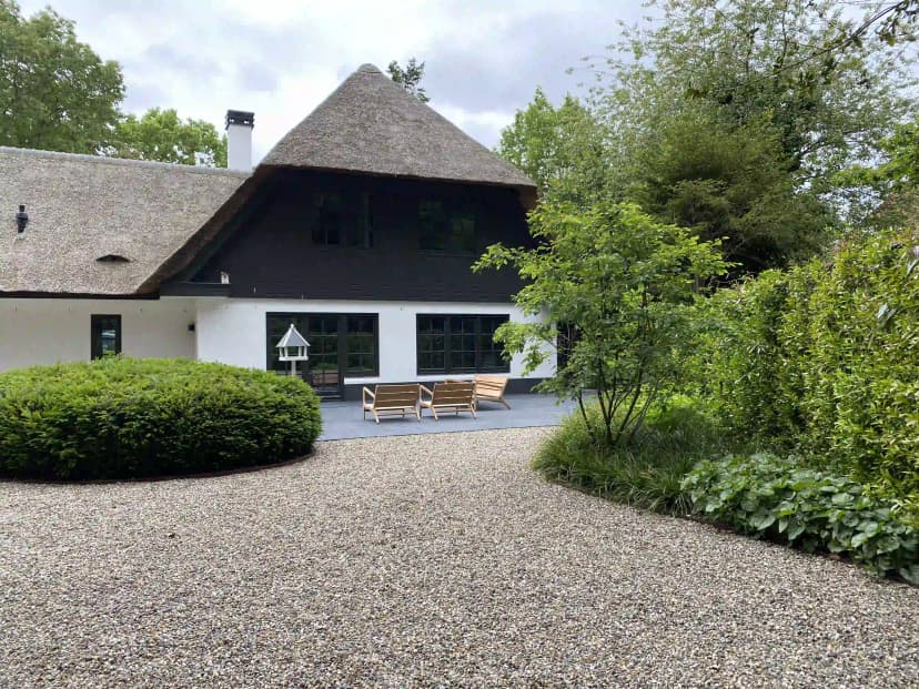 Boerderij met rieten dak en terras met houten stoelen