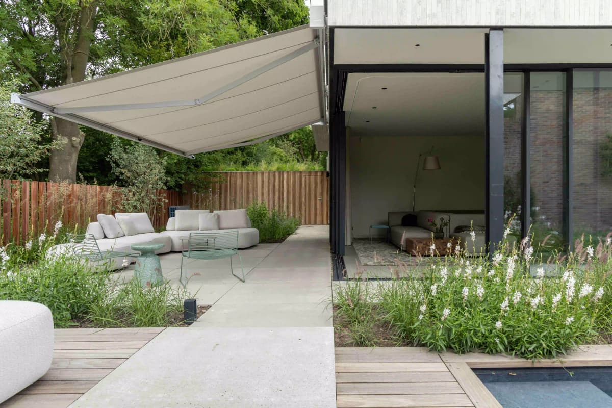 Covered terrace with lounge area and white flowering plants by pool