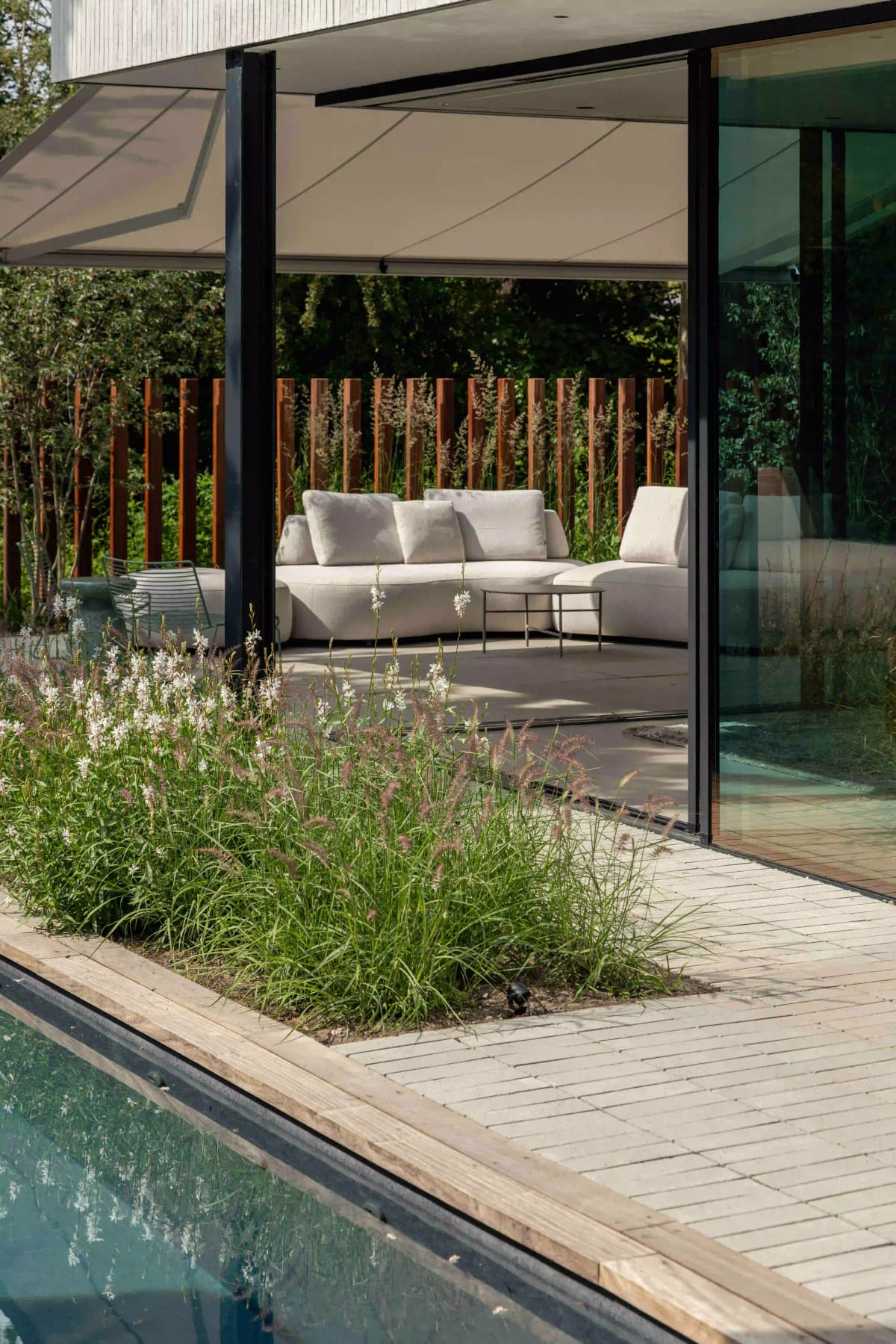 Covered terrace with outdoor seating and pool view with planting