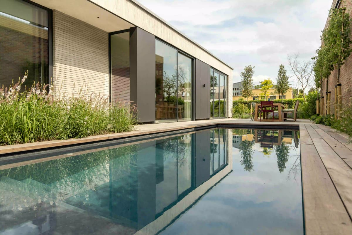 Pool view with modern architecture, wooden deck, and natural planting