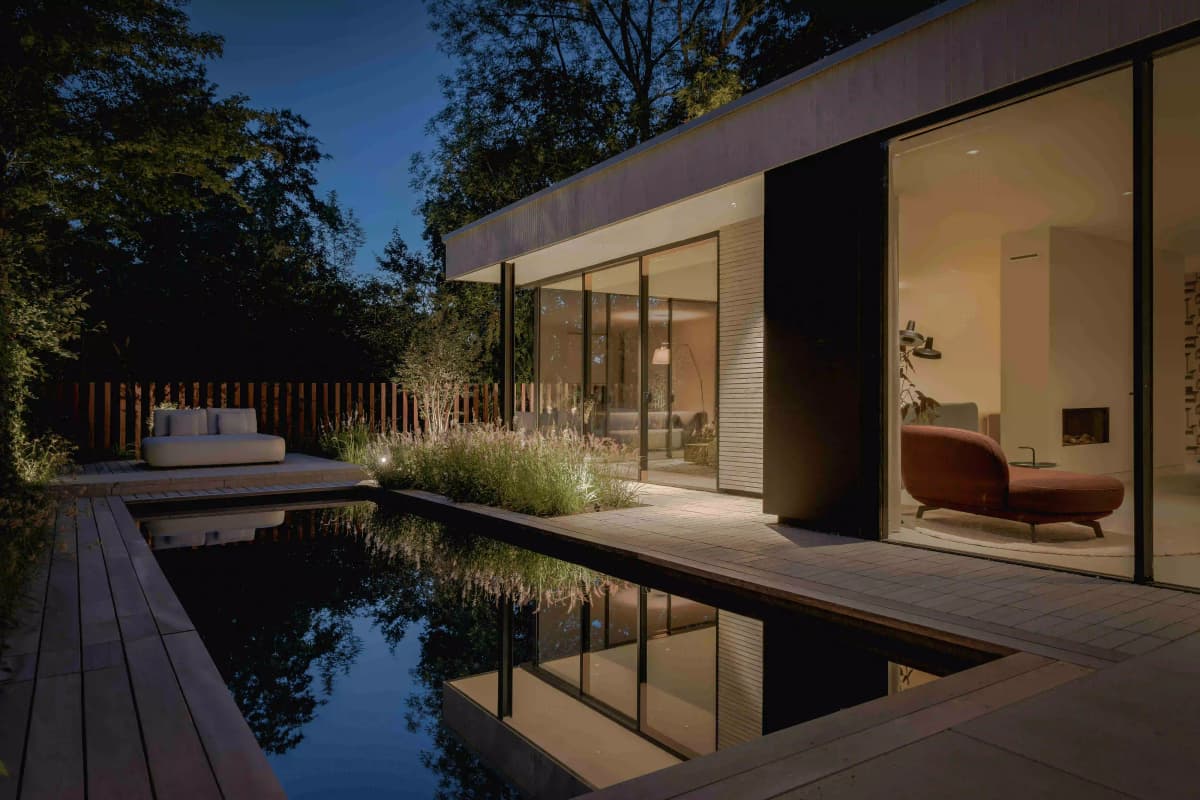 Evening pool reflection with illuminated modern house interior