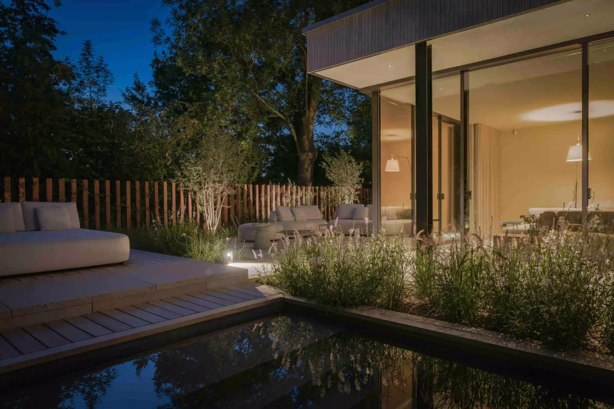 Evening view of pool with outdoor seating and warmly lit interior
