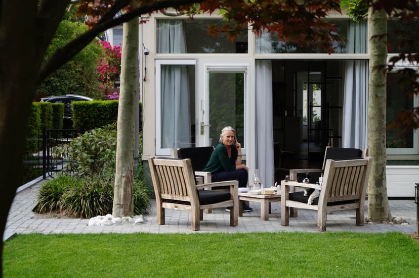 Terras onder dakplatanen met kleurrijke bloemenborder