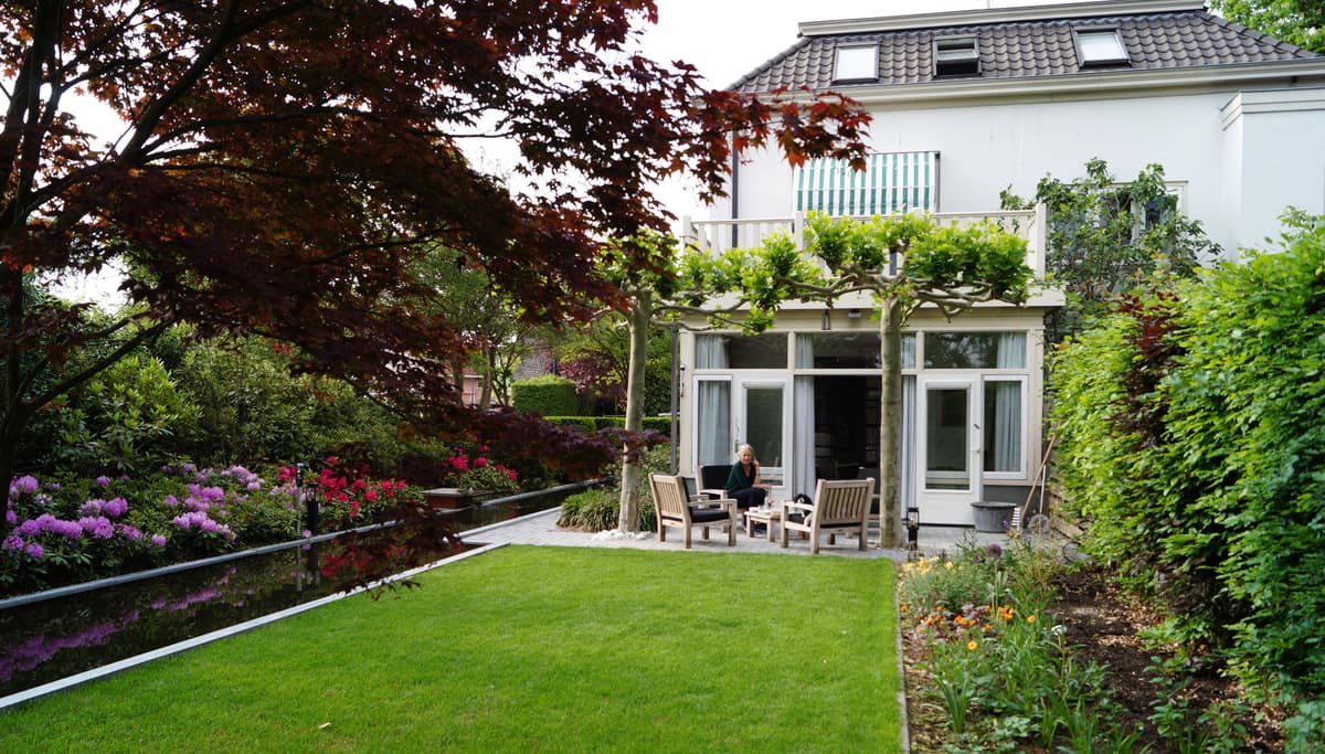 Klassieke tuin met langgerekte vijver, gazon en volgroeide bomen