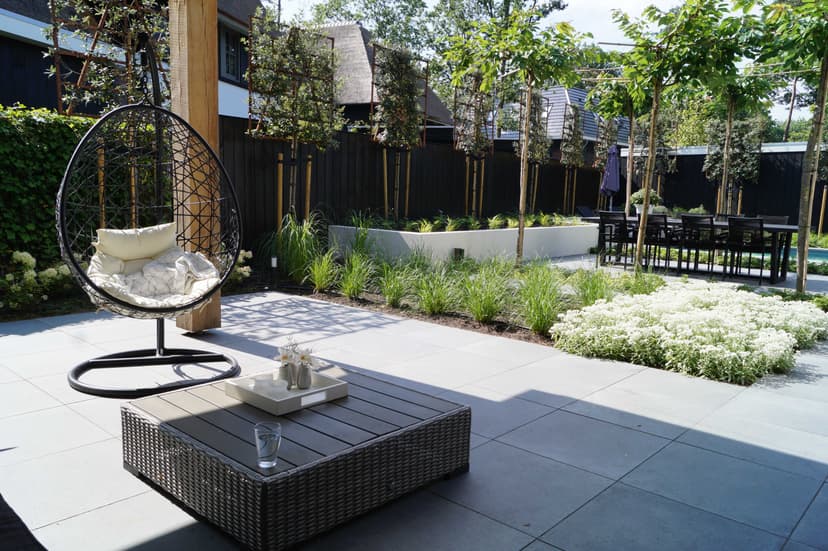 Moderne ei-stoel op terras met uitzicht op tuin en witte bloeiende planten