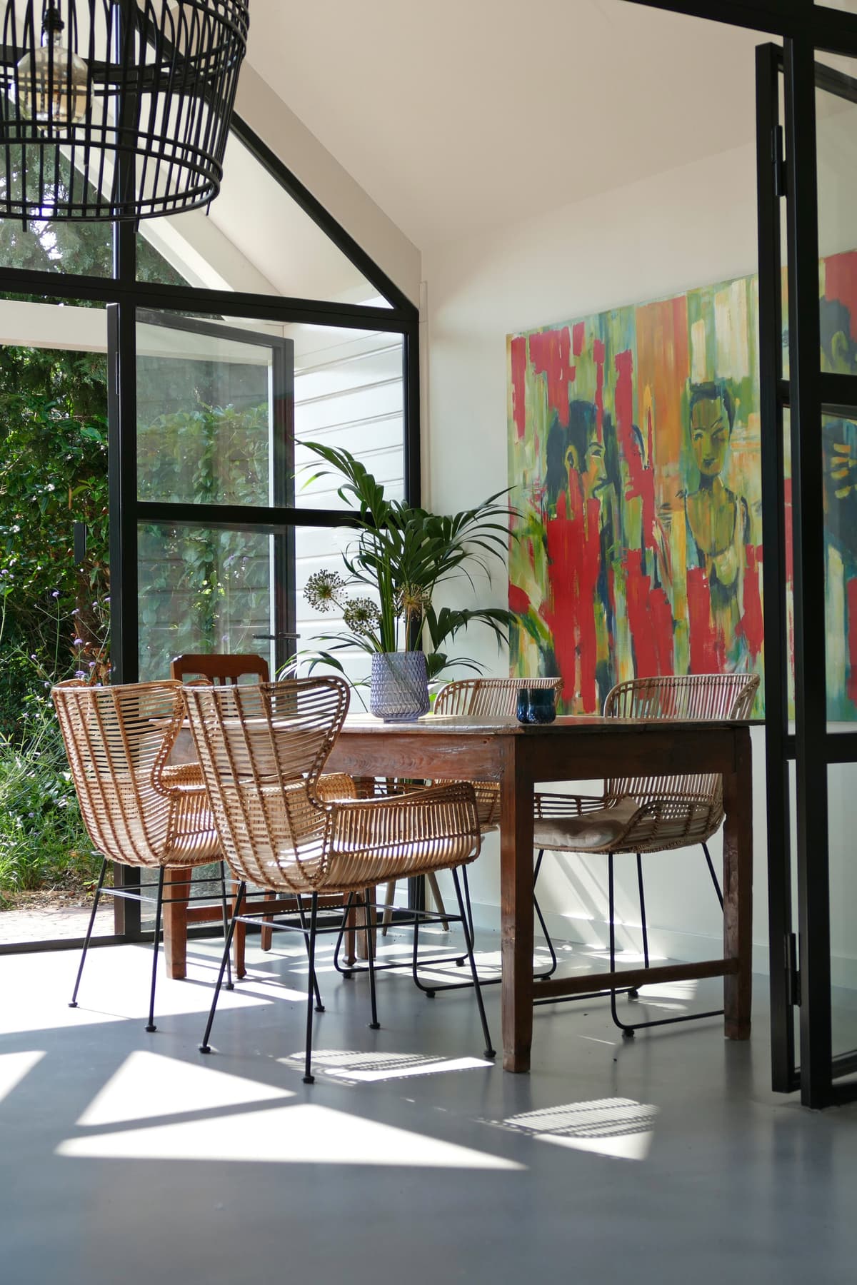 Eethoek met rieten stoelen en kleurrijke kunst aan de wand