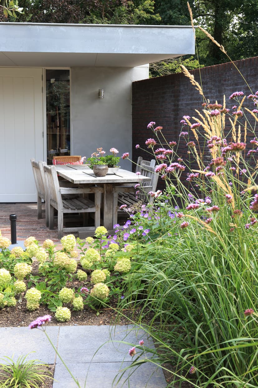Eettafel bij woning met pluimhortensia's en ijzerhard
