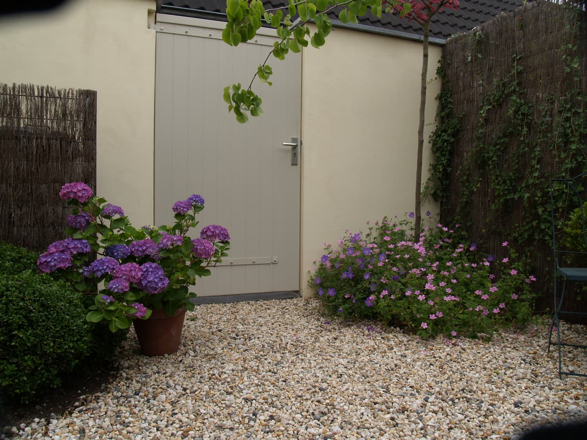 Tuinberging met grindvloer en paarse hortensia's