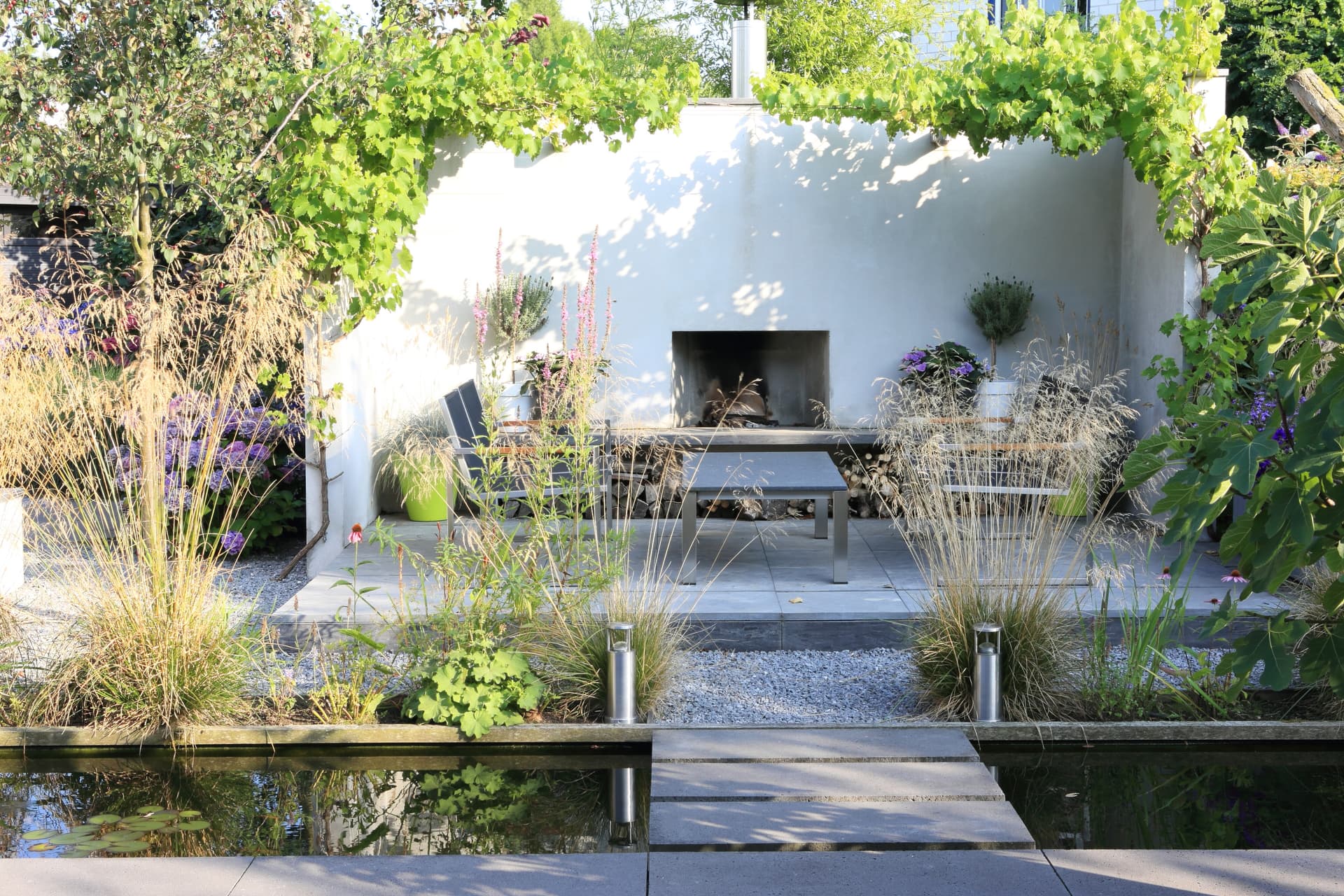Eigentijdse leeftuin met meerdere terrassen en moderne buitenhaard