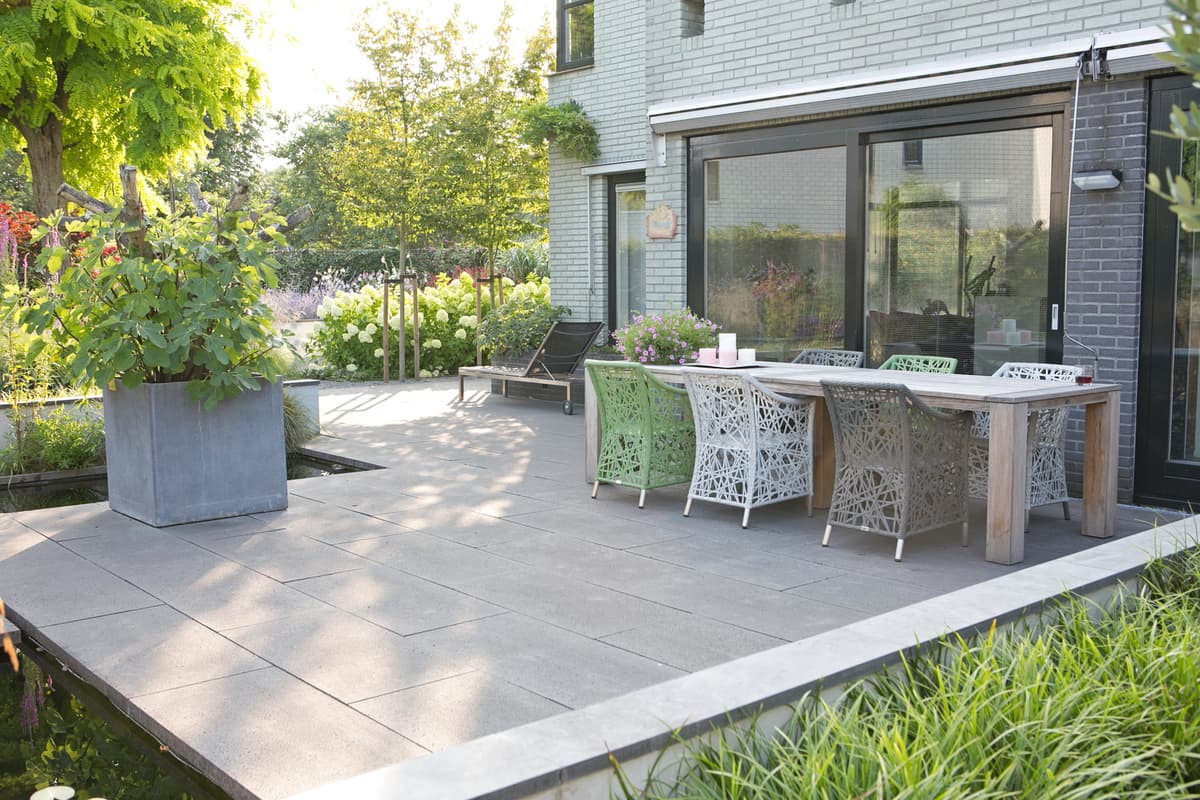 Terras met eettafel en witte rieten stoelen bij moderne woning